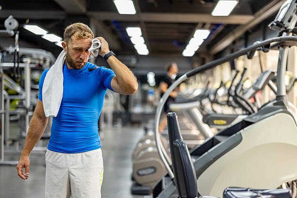 istock Man Wiping Sweat During Workout Session in Modern Gym Environment 2212814733