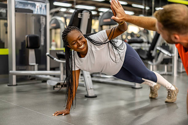 istock Happy Woman Exercising with Trainer in Modern Gym Environment 2212814773