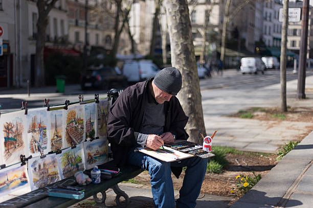 Paris, France: An artist working on his paintings on Quai de la Tournelle near the River Seine (5th arrondissement).