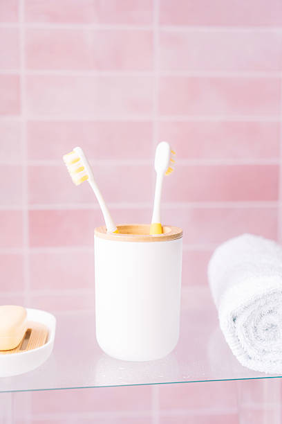 istock Two yellow toothbrushes in holder in bathroom on pink background 2212819777