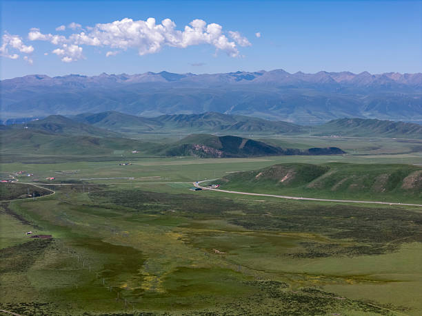 A serene mountain range under a clear blue sky, showcasing lush greenery and rolling hills. The scene is peaceful and expansive, ideal for nature photography or travel promotions.