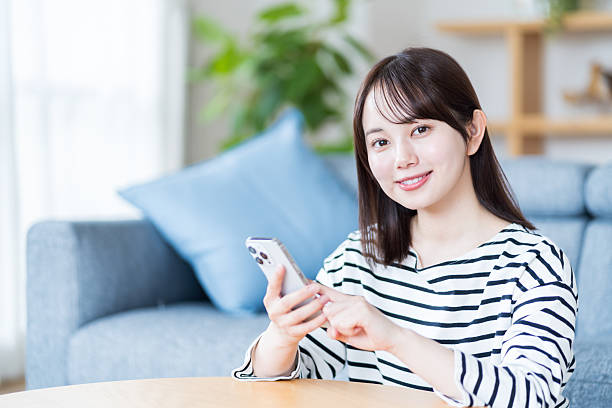 istock Young woman using smartphone in living room 2212822915