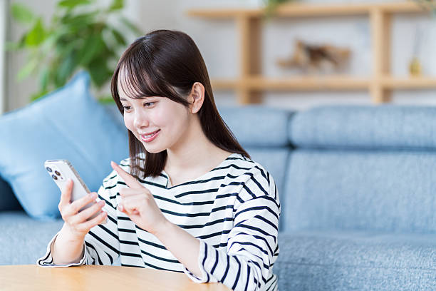 istock Young woman using smartphone in living room 2212822921
