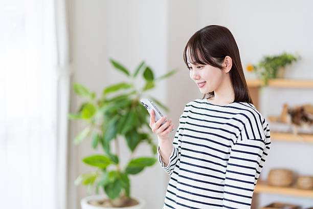 istock Young woman using smartphone in living room 2212823030