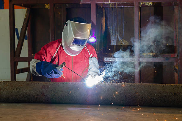 A group of dedicated workers in a metal workshop, skillfully welding a metal structure to perfection.