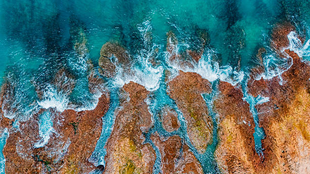 istock Rocky reef with clear blue waters and wave splashes, ideal summer travel background. 2212832296
