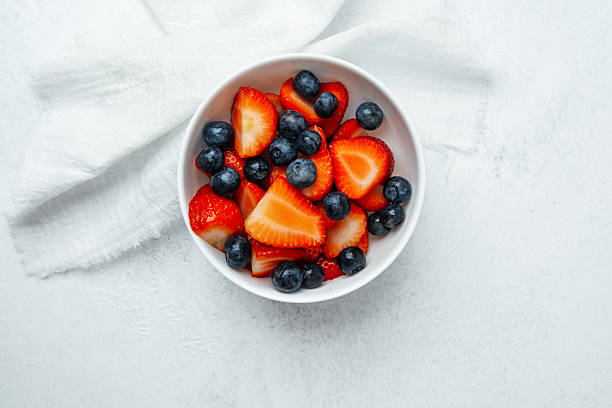 istock Fresh strawberries and blueberries in a bowl on a light surface 2212832467
