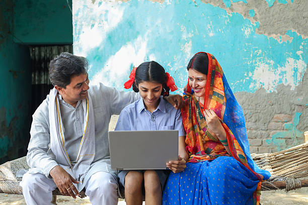 istock Rural indian parents with daughter in school uniform using lapto 2212838473