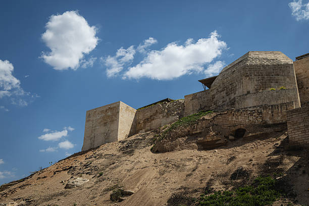Istanbul, Turkey - April 18, 2025: A view of the weathered stone walls and towers of the historic Gaziantep Castle in Turkey, set against a backdrop of a clear blue sky with scattered clouds. This imposing structure bears witness to centuries of history and architectural heritage.