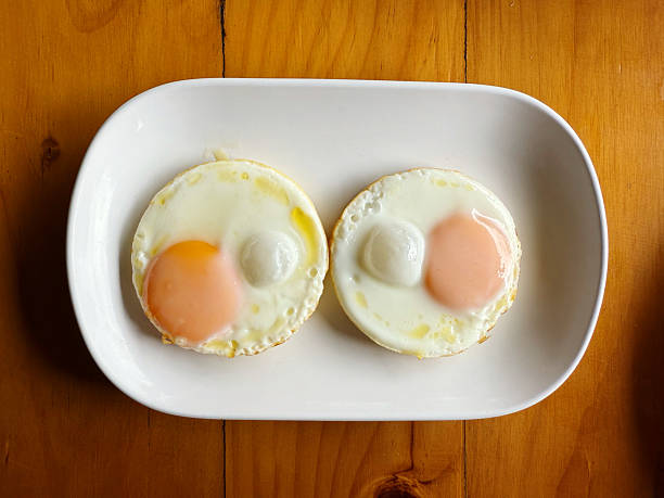 istock Fried eggs in white plate on wooden background. Top view. 2212840939