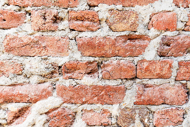 istock Old brick wall with weathered red bricks and thick, crumbling mortar 2212842866
