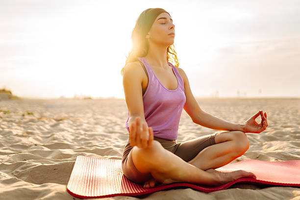 istock Sporty woman doing stretching exercise on yoga mat on sunset beach. 2212846484