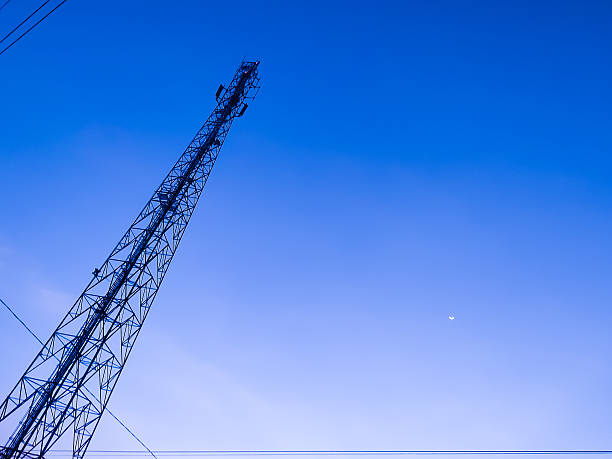 istock Tall Communication Tower Against Clear Blue Sky with Visible Crescent Moon 2212848342