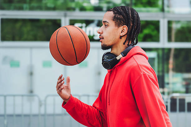 istock young man throwing up basketball while walking on streets in city 2212849622