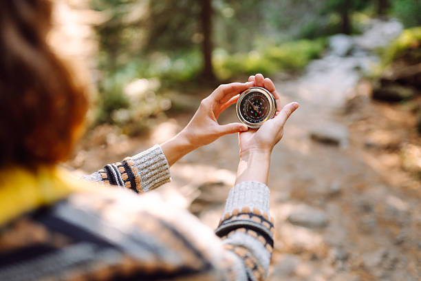 istock A back view of a female hiker with a backpack and a compass on a hiking forest path in the rays of the sunset. 2212850151