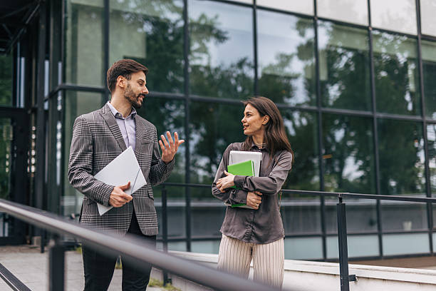 istock Two young professionals talking outside office building 2212856291