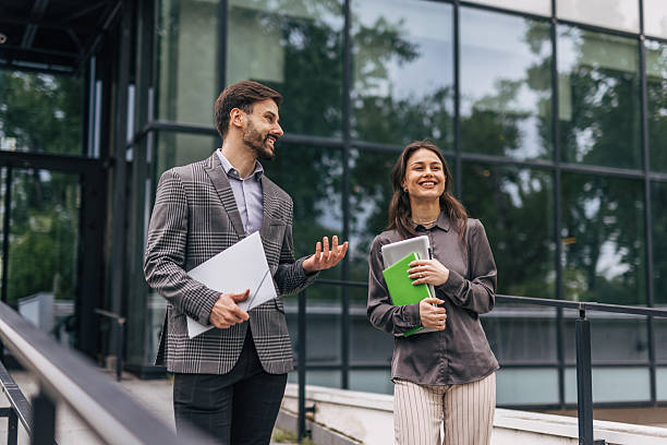 istock Two smiling business people walking and talking outside office building 2212856295