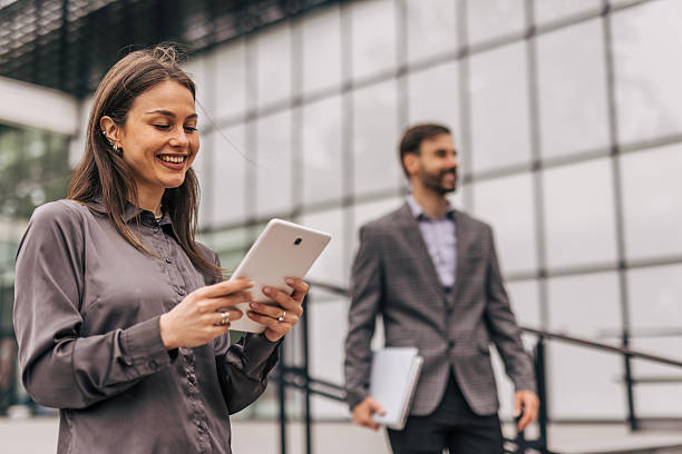 istock Businesswoman smiling and using digital tablet outside office building 2212856393