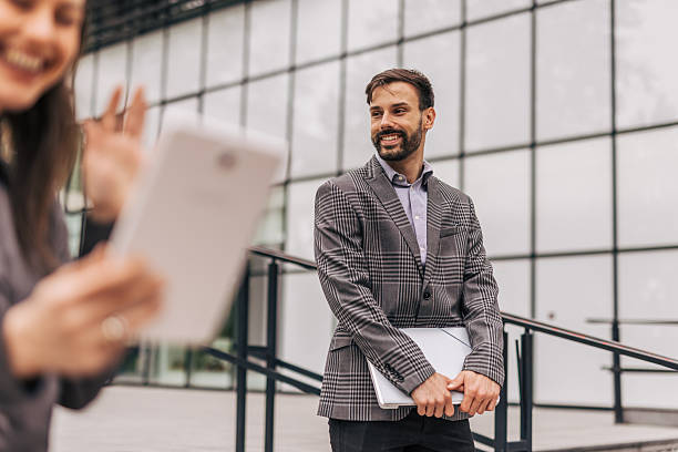 istock Businessman holding laptop and talking with colleague using tablet 2212856425
