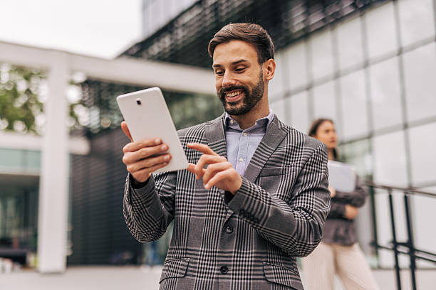istock Smiling businessman using digital tablet outside office building 2212856459