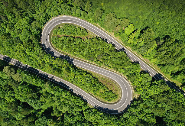 istock Aerial drone view of winding road between green forest 2212858203