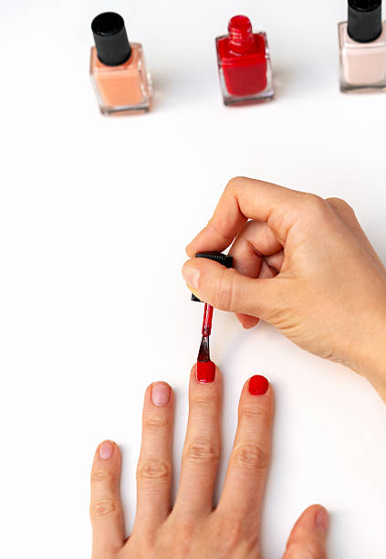 istock Female applying red nail polish  at home 2212860061