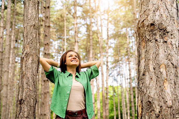 istock Happy woman with hands behind her head enjoying walking in forest. 2212861012