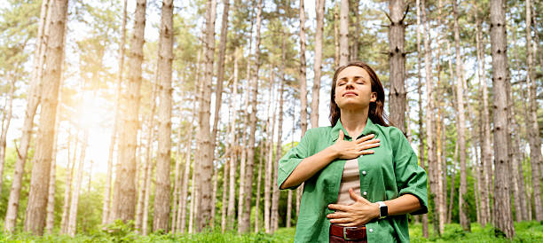 istock Healthy woman standing in forest and practising breathing exercise 2212861013
