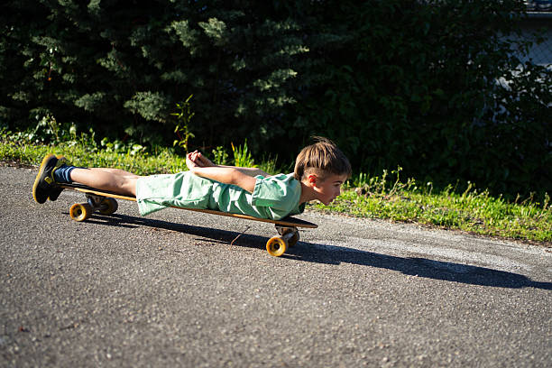 istock Child lying on skateboard going downhill on asphalt road 2212862323