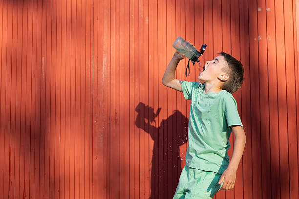 Child runner at the end cross-country running competition. Drinking water.