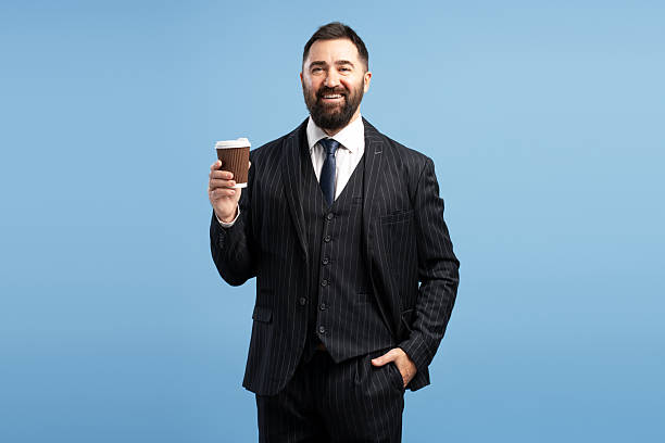 istock Smiling businessman holding takeaway coffee on blue background 2212863346