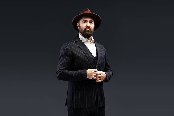 istock Serious businessman adjusting his suit while wearing a hat and looking at the camera 2212863357