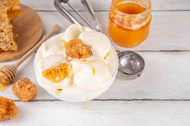 Custard base Milk and honey ice cream, sweet summer frozen dessert, bowl of creamy homemade honey taste gelato with honeycomb topping and honey drizzles