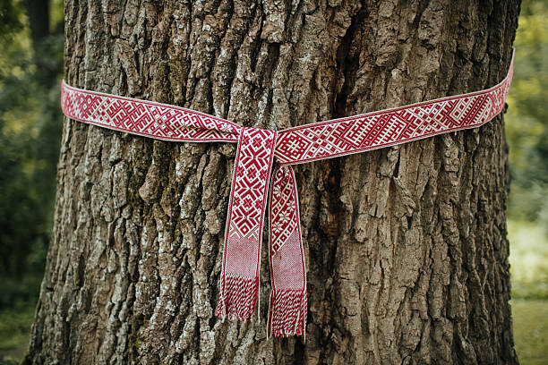 istock Traditional Red Woven Belt Tied Around Tree Trunk 2212865770