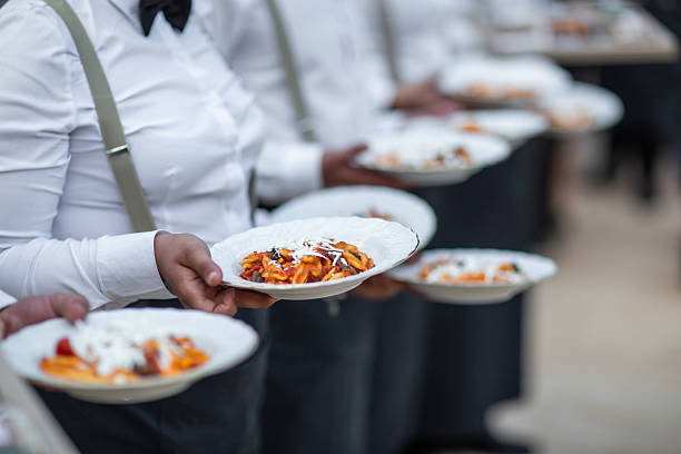 Waiters Serving Freshly Plated Pasta with Cheese Topping