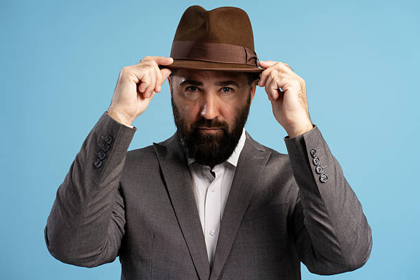 istock Elegant businessman adjusting his brown fedora hat 2212866059