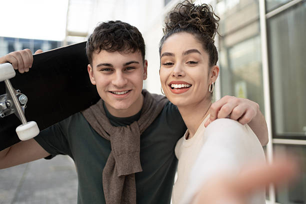 istock Young couple taking a selfie while holding skateboard 2212875770