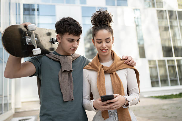 istock Young couple looking at smartphone and carrying skateboard 2212876824