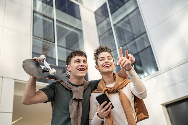 istock Young couple having fun with skateboard and smartphone in urban setting 2212877945