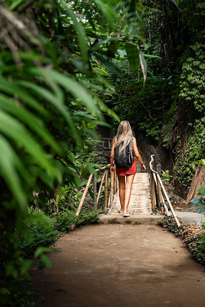 istock Tourist walking on bamboo bridge in lush tropical forest 2212881457