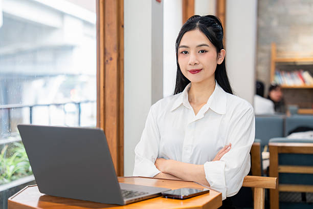 istock Professional woman posing with laptop in a bright cafe setting showcasing confidence and style 2212881505