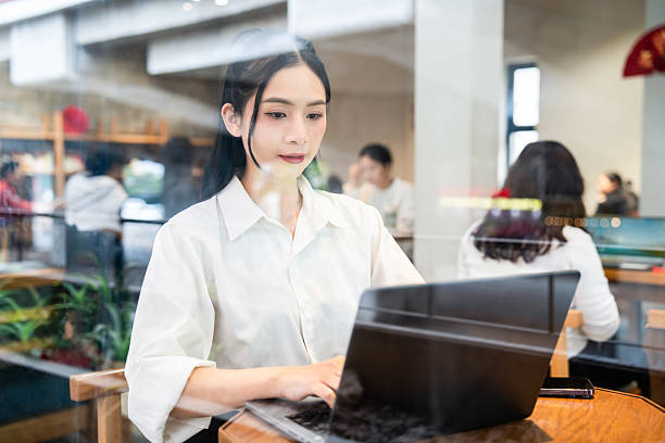 istock Young woman working on laptop in cafe Focus and concentration on her remote work environment 2212881886