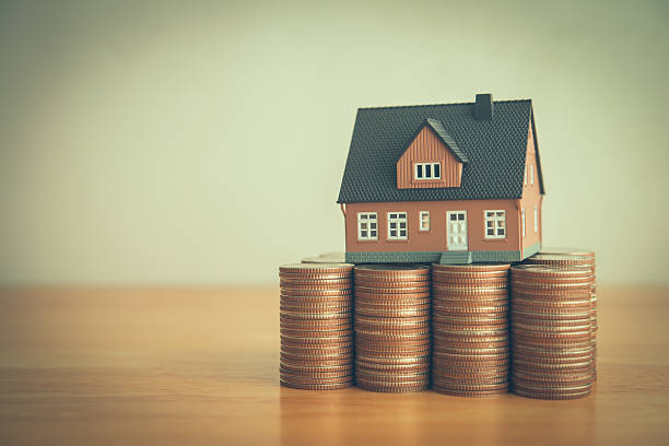istock House on heap stack coins on wooden table white wall background copy space. 2212886928