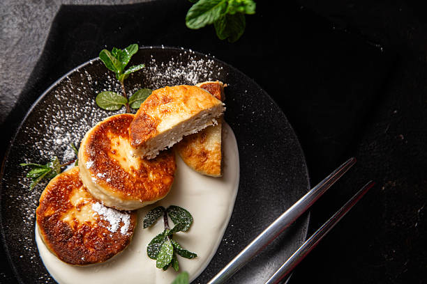 istock Cheesecakes with cream sauce and mint in a black plate on the table. Breakfast 2212887507