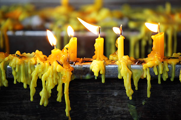 A close-up of yellow candles dripping wax with flickering flames, creating a warm and inviting atmosphere. Ideal for projects related to rituals or decoration.
