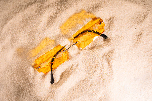 Yellow razor shaped sunglasses on clean sand.