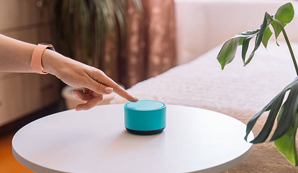 istock A woman's hand touches her finger to a blue smart speaker on the table 2212892449