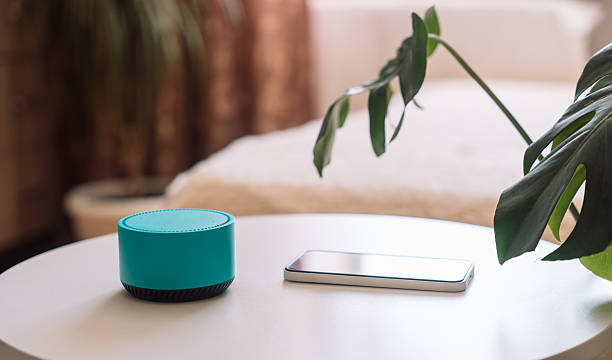 istock Blue wireless smart speaker on white table with phone in room 2212892525
