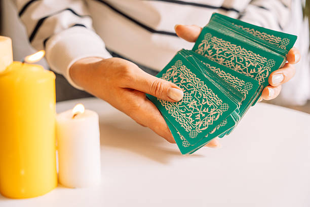 Lady tarot reader shuffles tarot cards in front of candles.