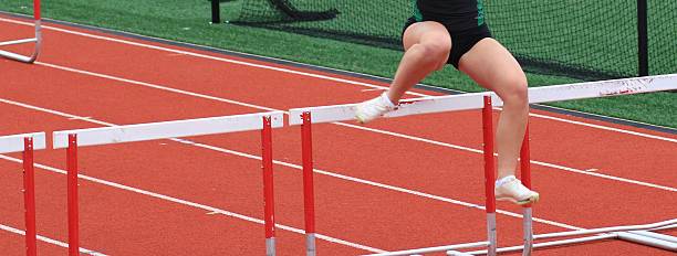 istock Female hurdler jumping over a hurdle during a track race 2212897085